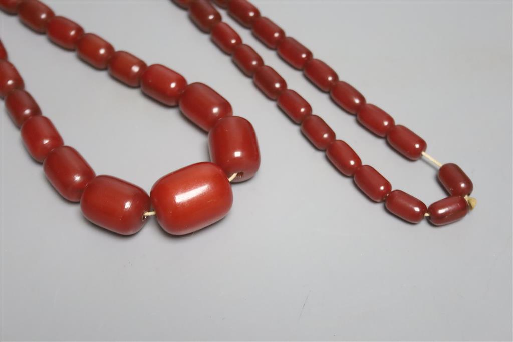A single strand graduated simulated cherry amber barrel shaped bead necklace, 90cm, gross 87 grams.